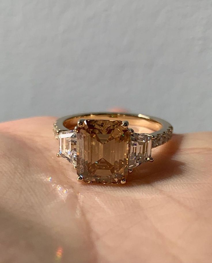 a woman's hand holding an orange and white diamond ring