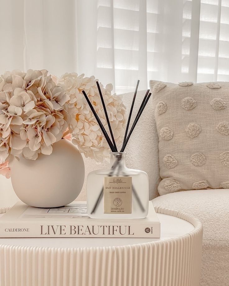 a white table topped with a vase filled with flowers next to a couple of books