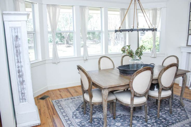 a dining room table with chairs and a rug on the floor in front of it