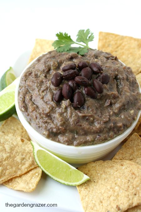 a white bowl filled with black bean avocado dip surrounded by tortilla chips