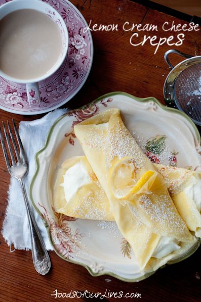 lemon cream cheese crepes on a plate next to a cup of coffee and tea