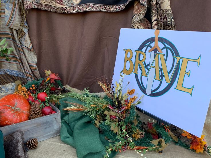 a sign that says brave next to some pumpkins and other autumn decorations on a table