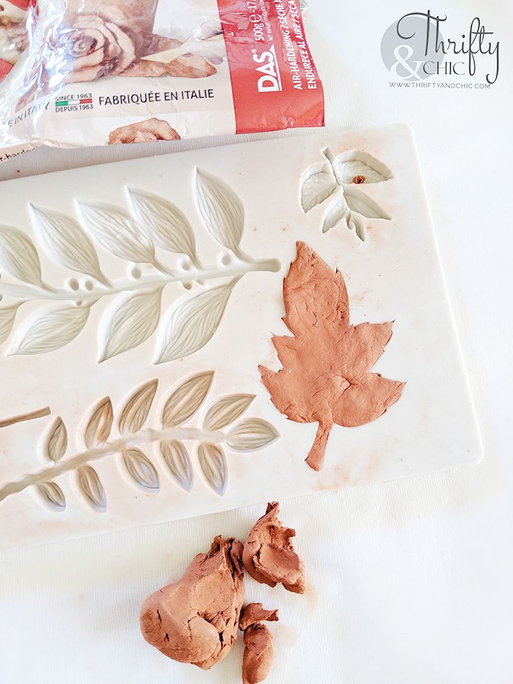 the cookie cutters are laying on top of the frosting sheet and next to some leaves