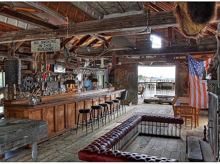 an old fashioned bar with lots of stools and american flags hanging from the ceiling