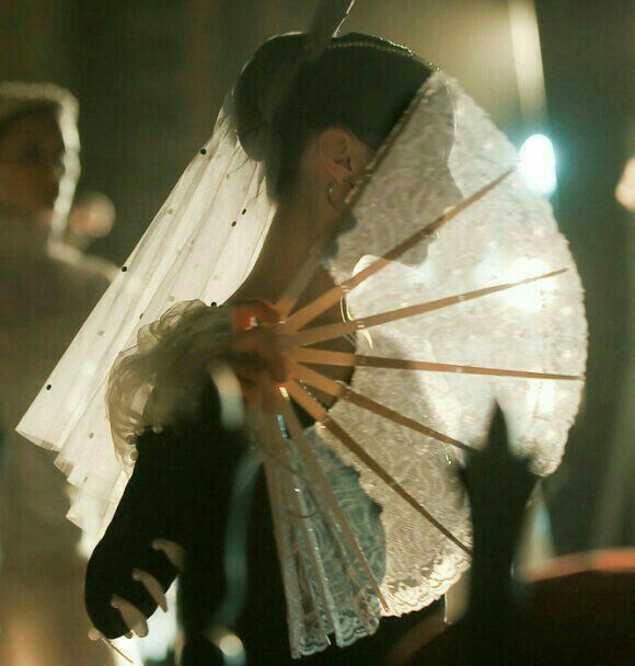 a woman holding an umbrella in front of her face while standing next to other people