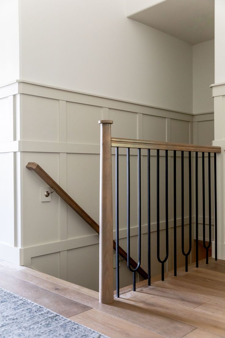 an empty room with a stair case and wooden handrail in the center, along with a blue rug on the floor