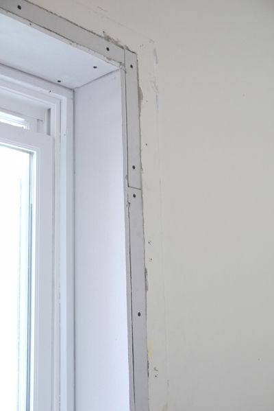 the corner of a room that is being painted with white paint and some holes in it