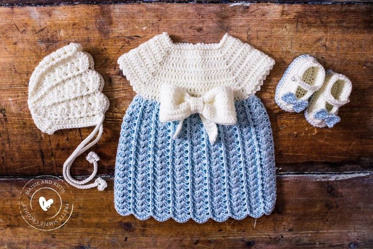 a crocheted baby outfit, booties and hat on a wooden surface