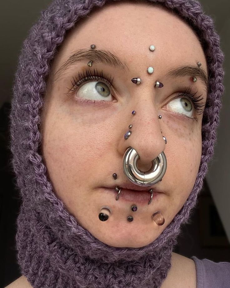 a woman with piercings on her nose wearing a purple scarf and headdress