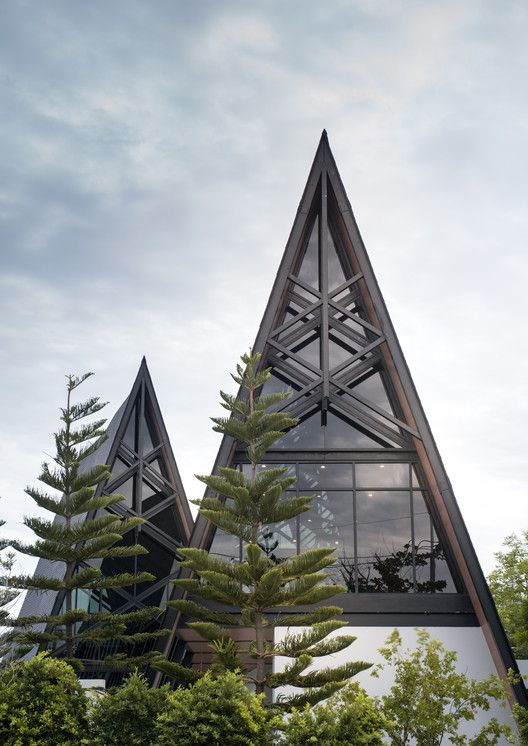 two triangular shaped buildings with trees in the foreground