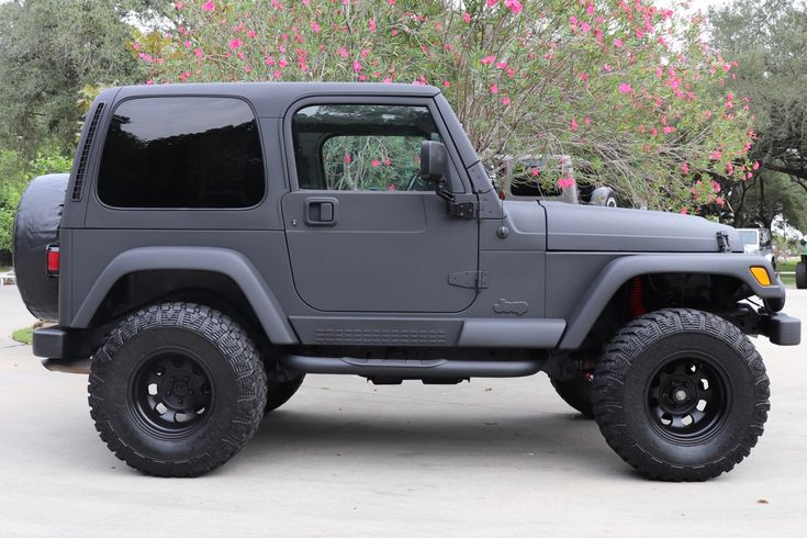 a gray jeep is parked in front of some trees