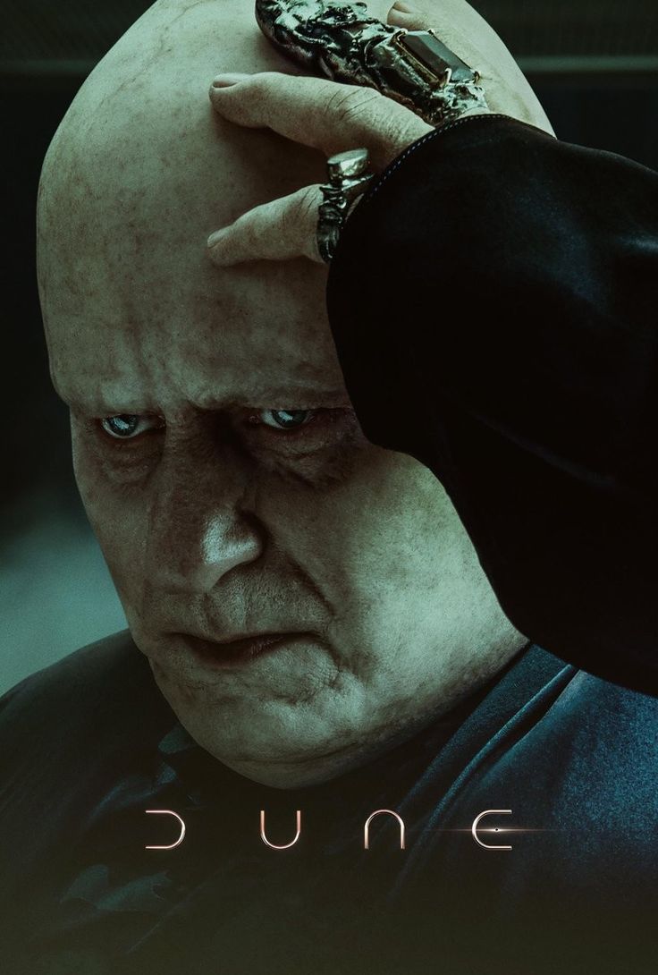 an older man holding his hands to his head in front of the poster for dune