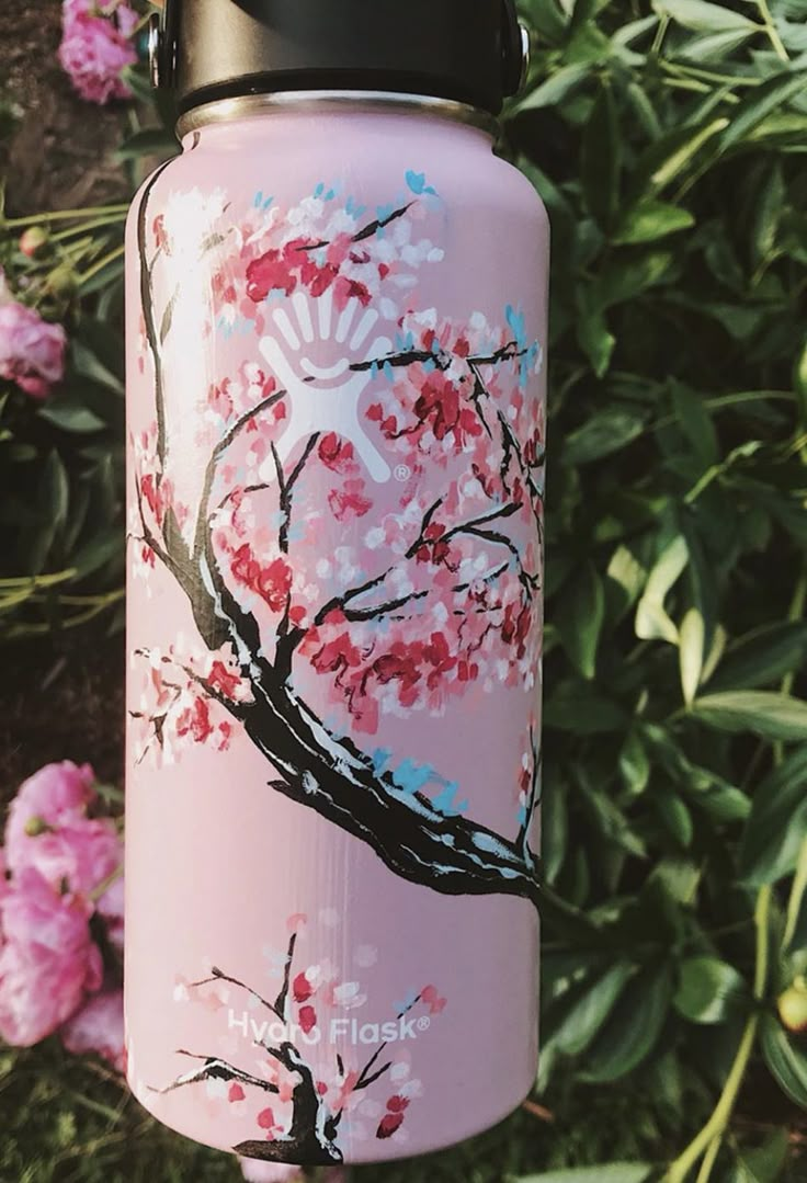 a pink water bottle with an image of a tree and flowers painted on the side