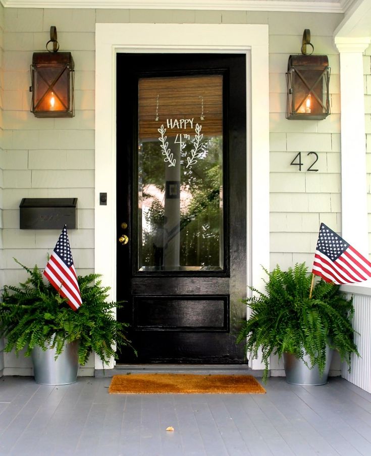 two potted plants on the front porch of a house with an american flag and happy fourth