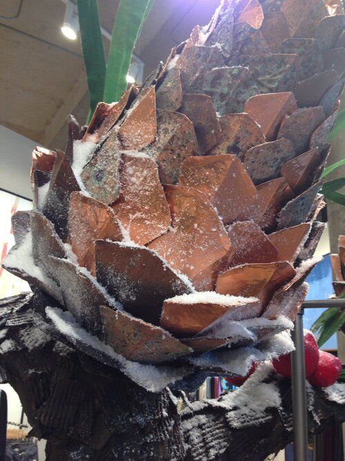 a large pineapple sitting on top of a pile of wood next to a plant