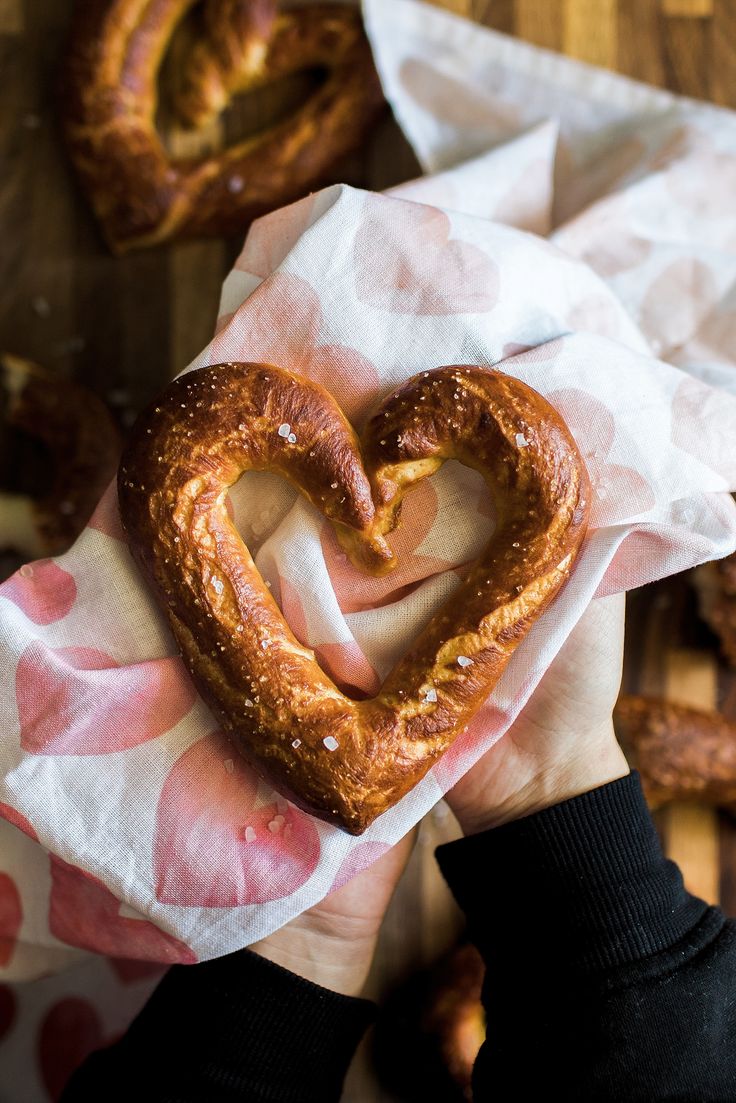 a person holding a heart shaped pretzel in their hands