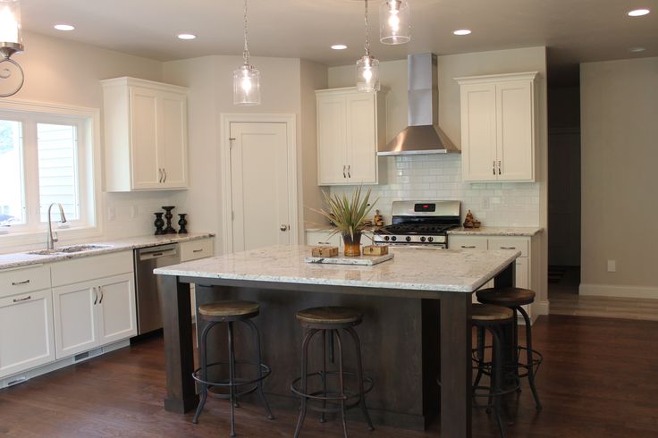 a kitchen with white cabinets and an island in front of the stove top oven is shown