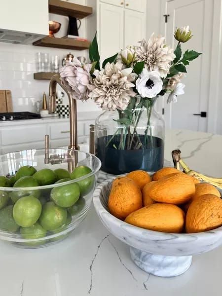 two bowls filled with fruit sitting on top of a kitchen counter next to a sink