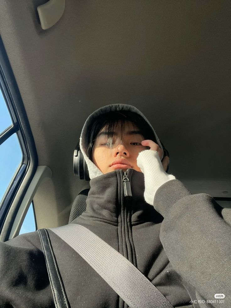 a young boy sitting in the back seat of a car wearing headphones