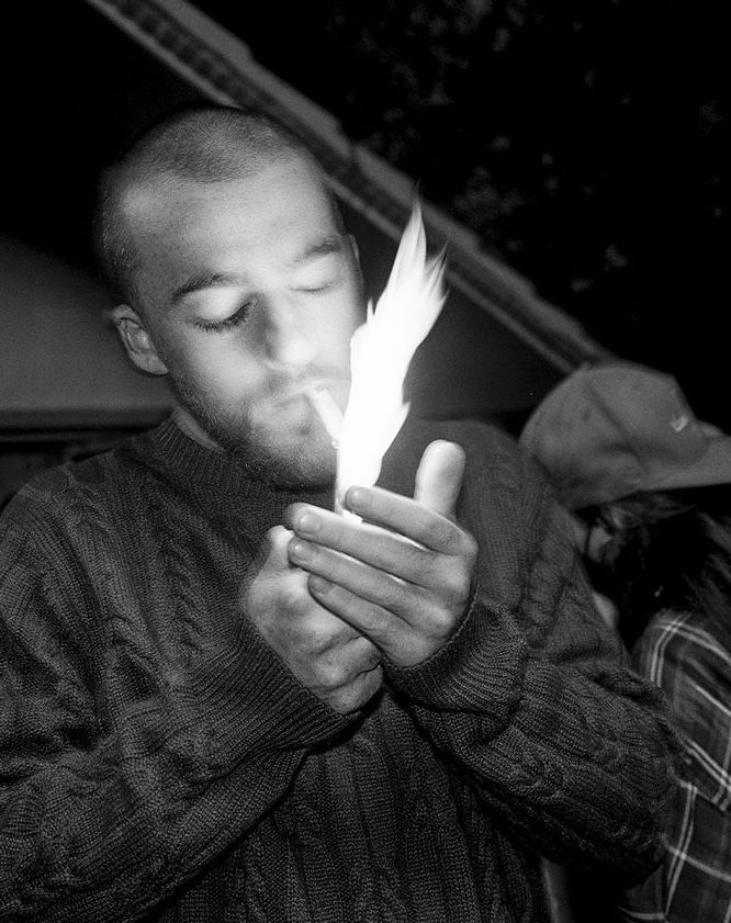 a man holding a lit candle in his hands while looking down at the flame that is coming out of it