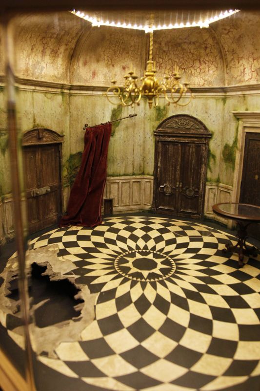 a room with a checkered floor, chandelier and two doors in it