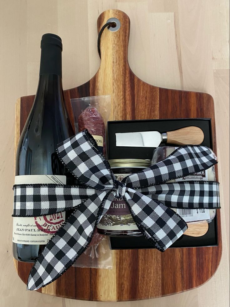 a wooden cutting board with wine, cheese and other items