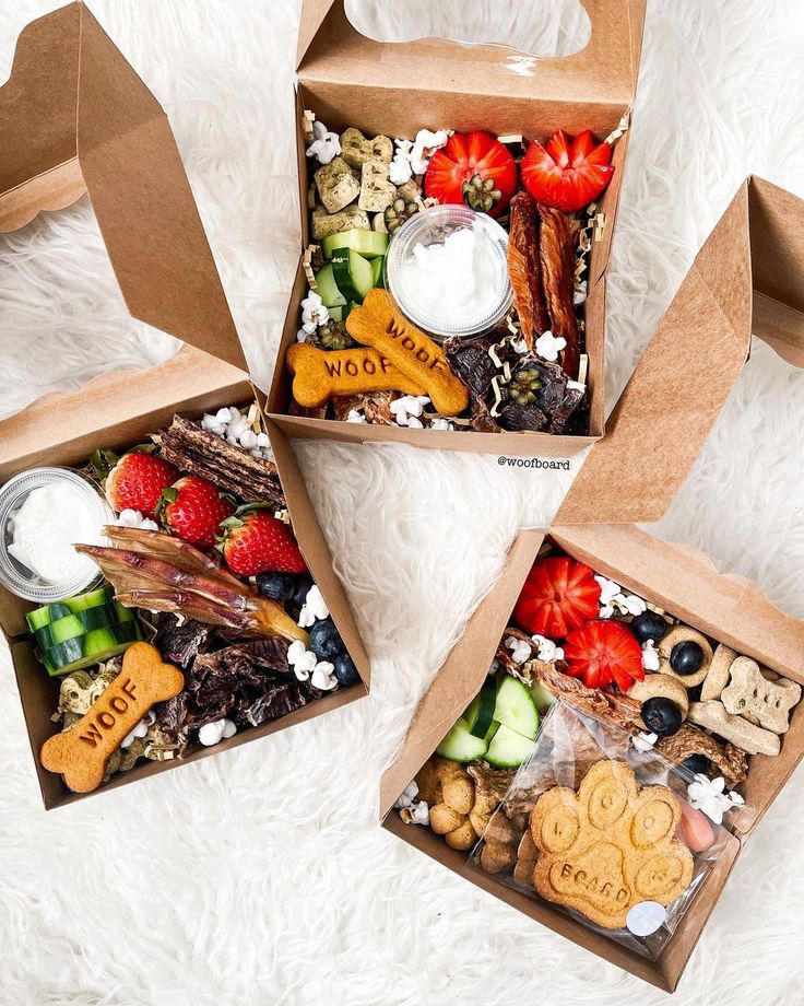 three boxes filled with different types of food on top of a white rug and one is open to show the contents