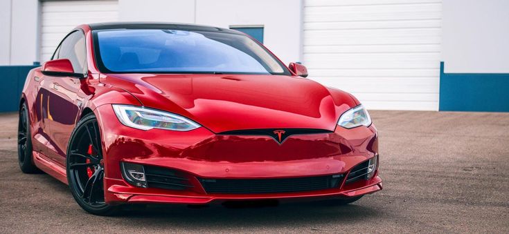 a red tesla parked in front of a building