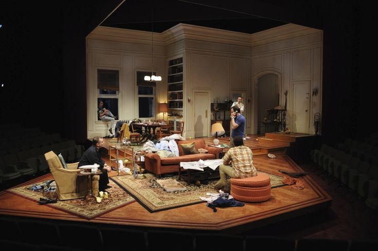 a group of people sitting around a living room on top of a wooden floor