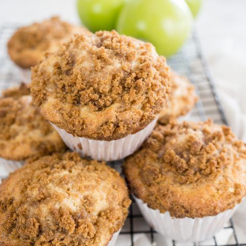 several muffins sitting on a cooling rack next to some green apple's