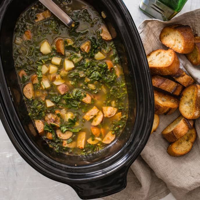 a crock pot filled with soup and potatoes