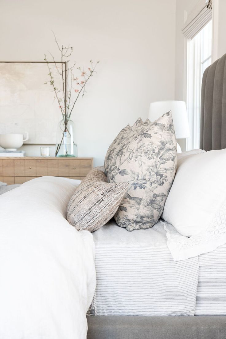 a bed with white linens and pillows on it's headboard in a bedroom