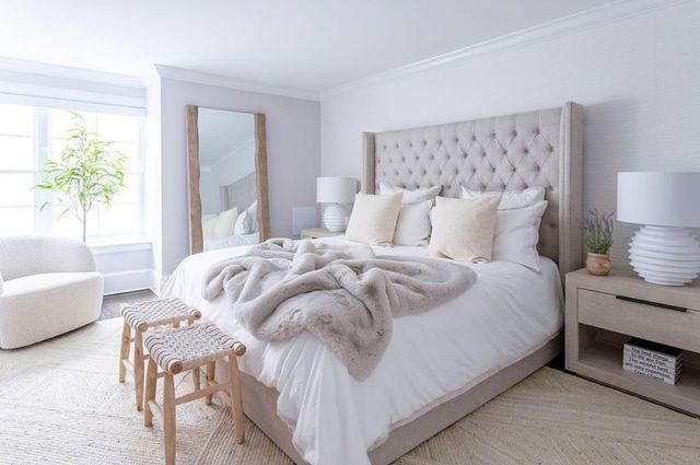 a bedroom with a large bed covered in blankets and pillows, two side tables next to the bed