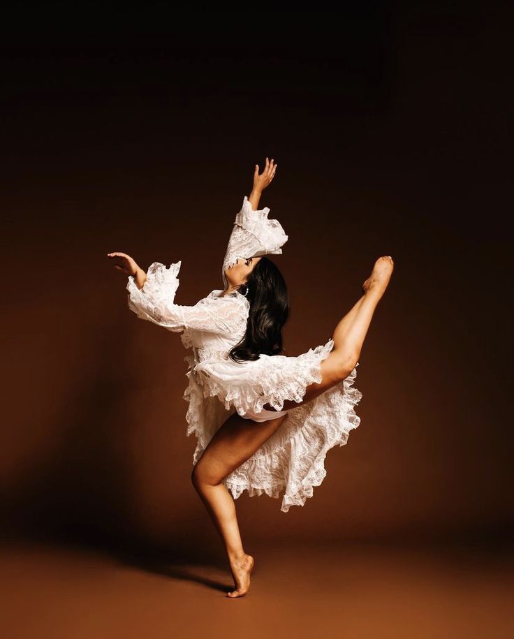 a woman in a white dress is dancing with her arms outstretched and legs spread out