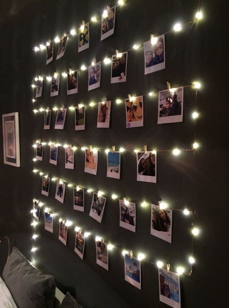 a bedroom with lights strung from the wall and pictures hanging on the wall above it