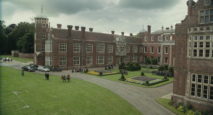 people are walking around in front of an old brick building with many windows on it