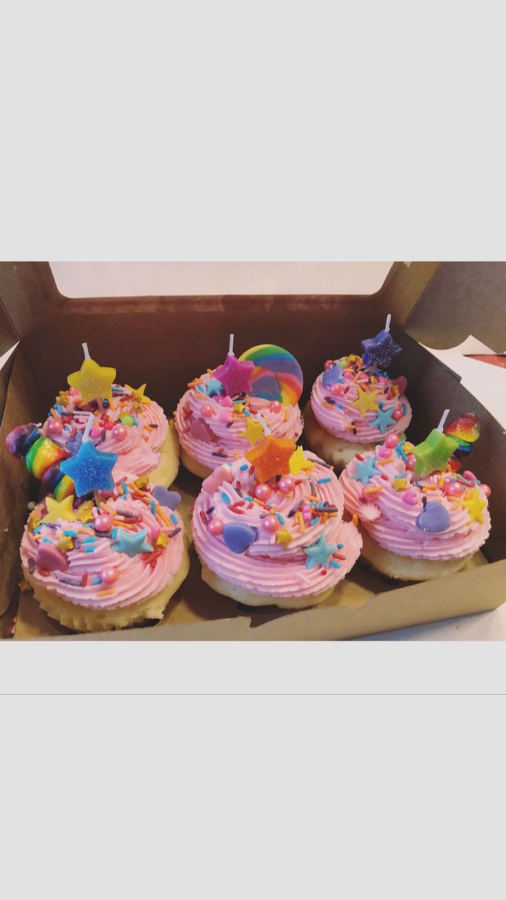 a box filled with cupcakes covered in pink frosting and sprinkles