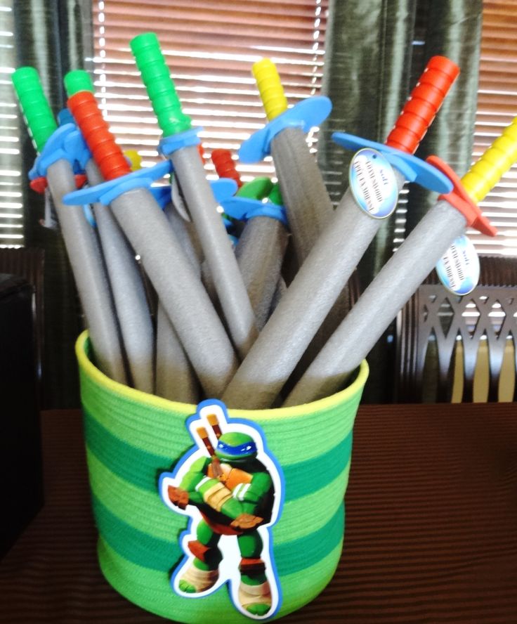 a green and white bucket filled with lots of plastic pens on top of a wooden table