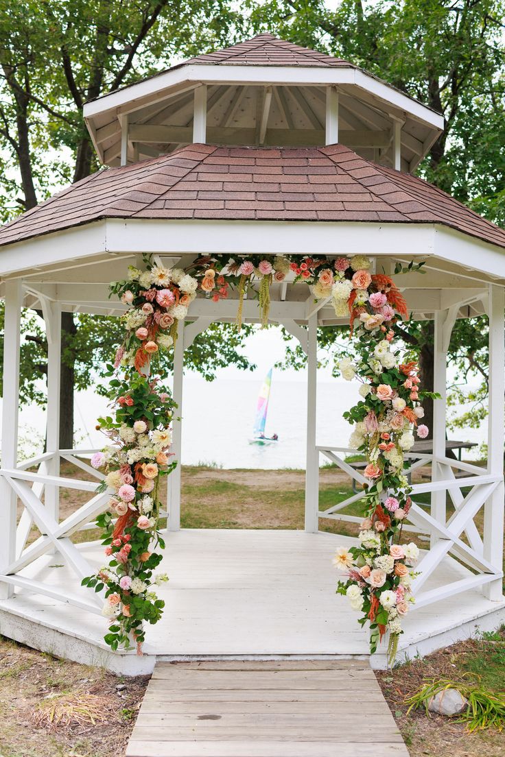 a white gazebo with flowers and greenery on it