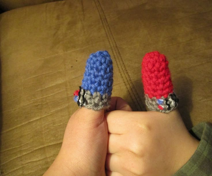 two small crocheted objects are held in the palm of a child's hand