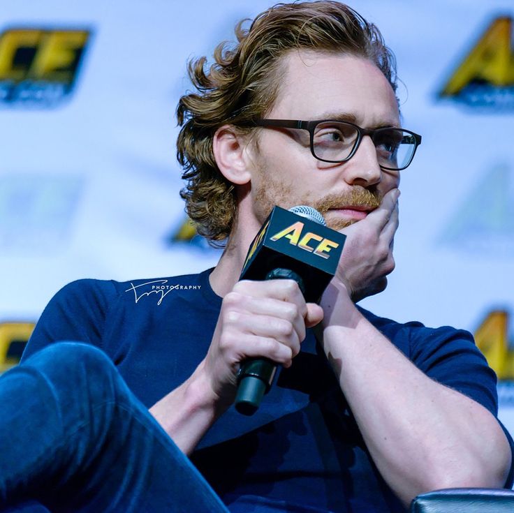 a man with glasses sitting in front of a microphone