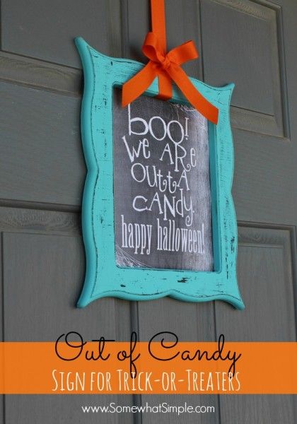 a sign for trick or treat hangs on the front door with orange ribbon and bow