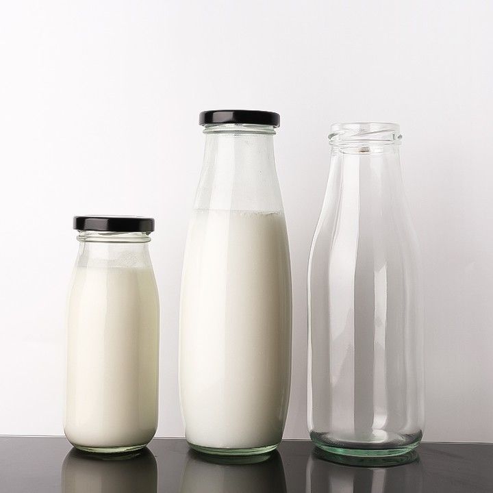 three glass containers with milk on a table