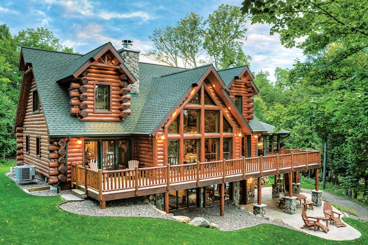 a large log cabin home with deck and covered porchs on the side of it