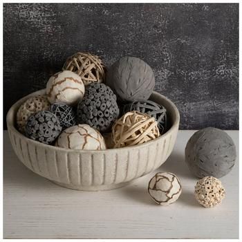 a bowl filled with lots of different types of balls on top of a white table