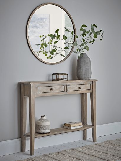 a wooden table with two drawers and a mirror on the wall above it in a living room