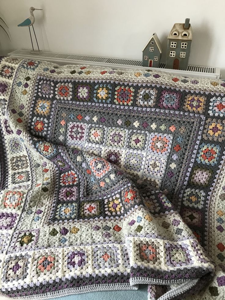 a crocheted granny blanket on top of a bed next to a doll house