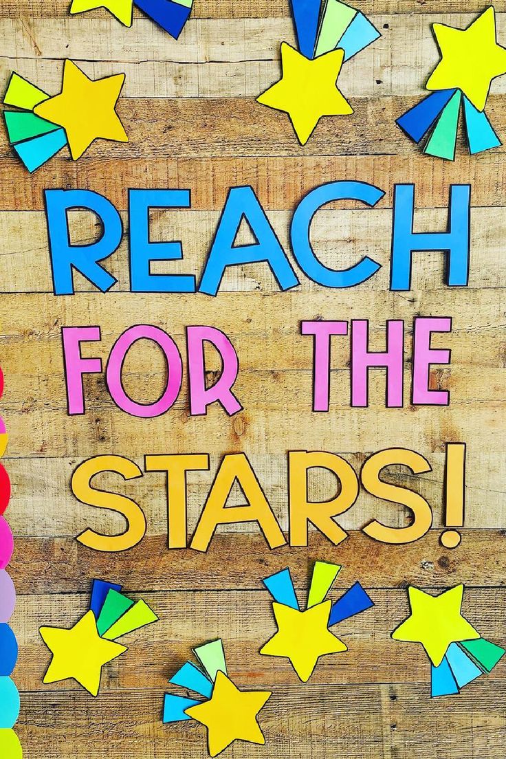 a sign that says reach for the stars on a wooden background with colorful paper stars