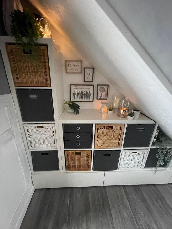 an attic bedroom with white walls and wooden flooring, baskets on the shelves below