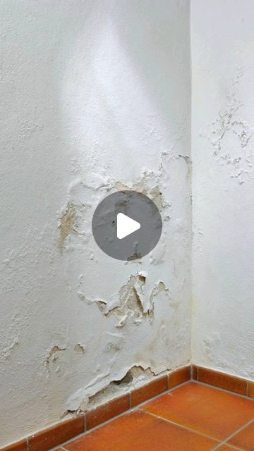 the corner of a room with peeling paint on it and a hole in the wall